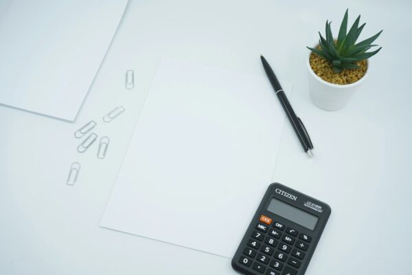 Calculator beside a pen on printer paper