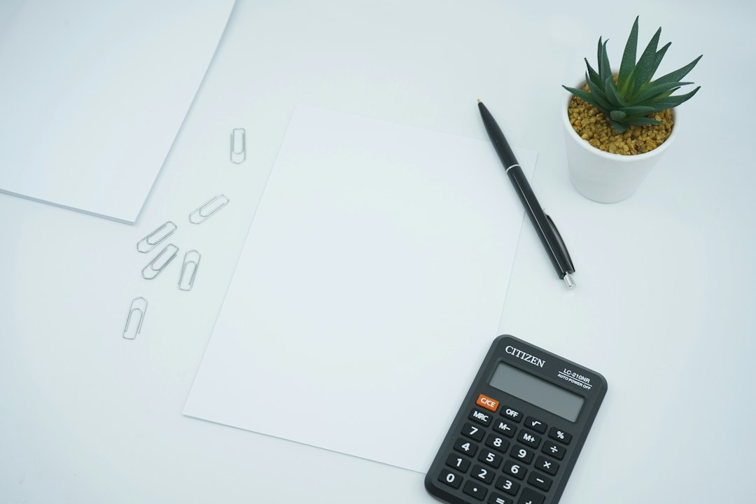 Calculator beside a pen on printer paper